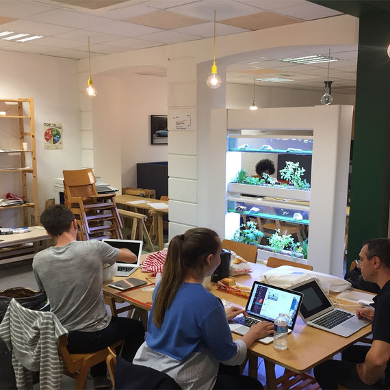 Baromate blanc installé dans un espace de travail partagé, équipe au travail sur une grande table devant le meuble