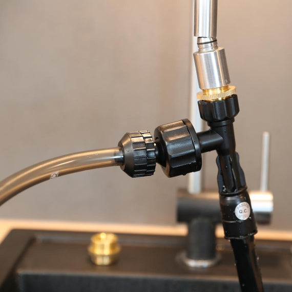 Pompe d'aspiration JBL vissée sous le robinet d'un évier, tuyau raccordé