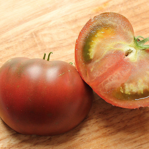 Tomate Noire de Crimée coupée en deux sur une planche : chair dense, peu de loges et peu de graines